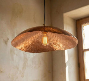 Copper pendant light hanging in a room with natural light