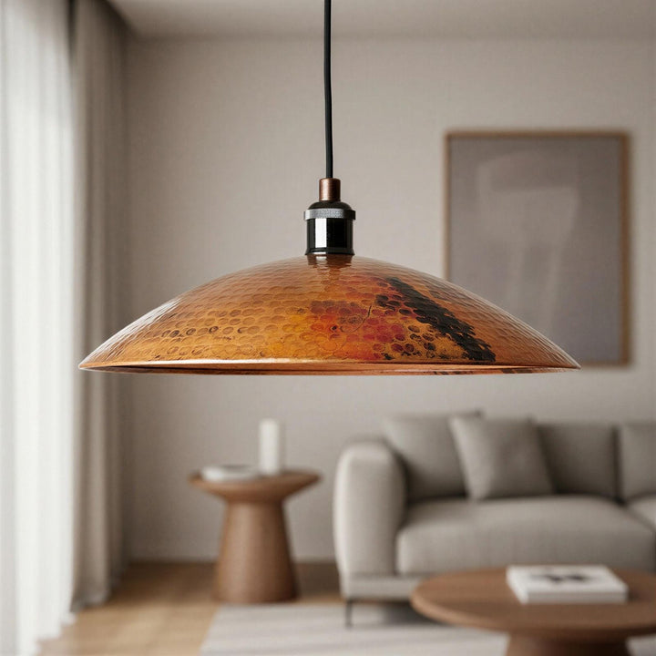 Copper pendant light hanging in a living room with a sofa and coffee table.
