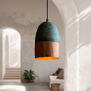 Pendant light with a green and wooden design hanging in a room with a plant and sofa.