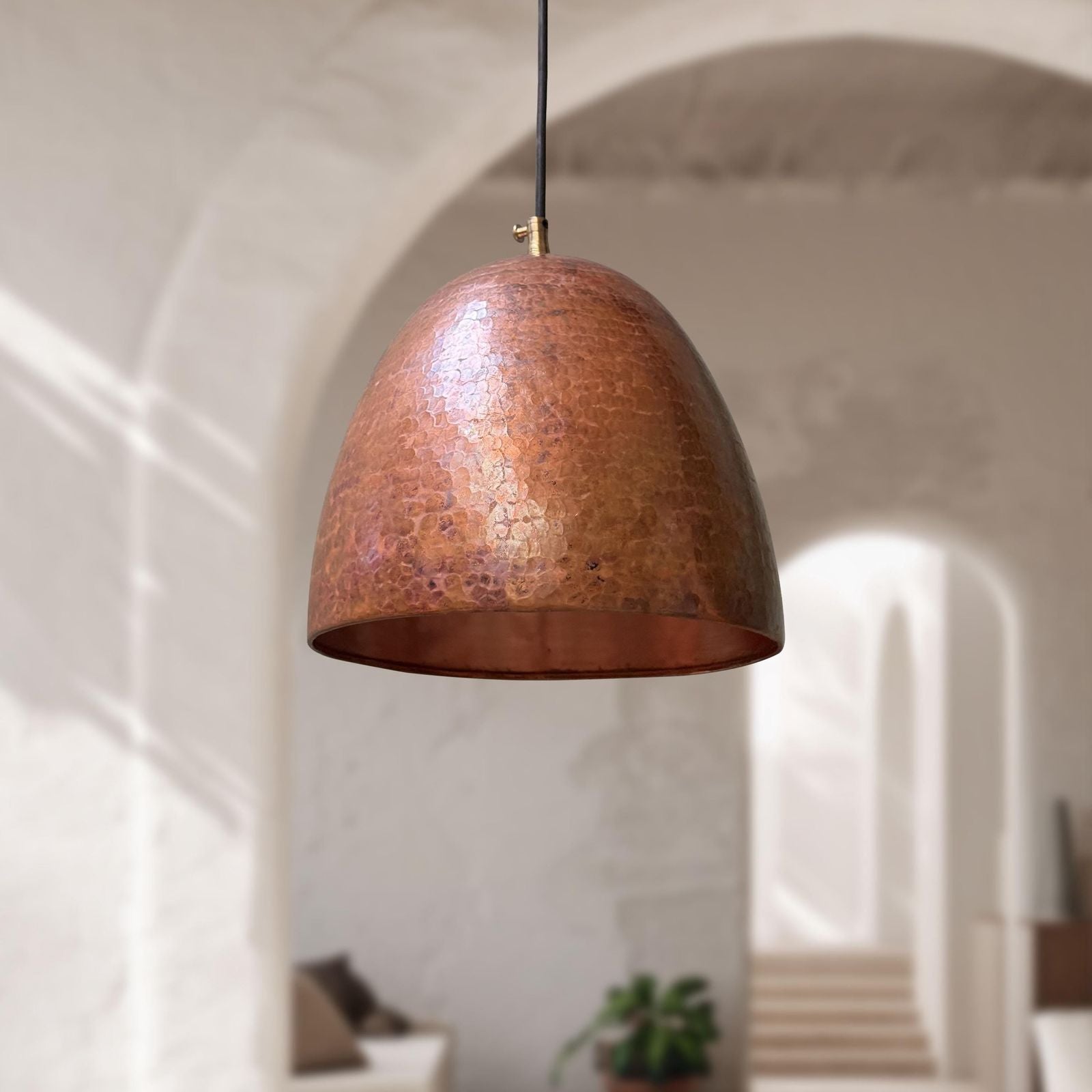 Copper pendant light hanging in a room with soft lighting