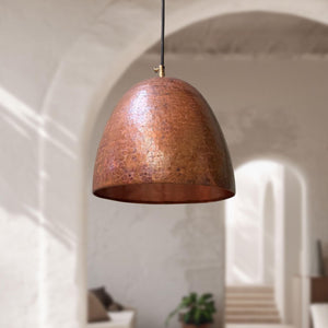 Copper pendant light hanging in a room with soft lighting