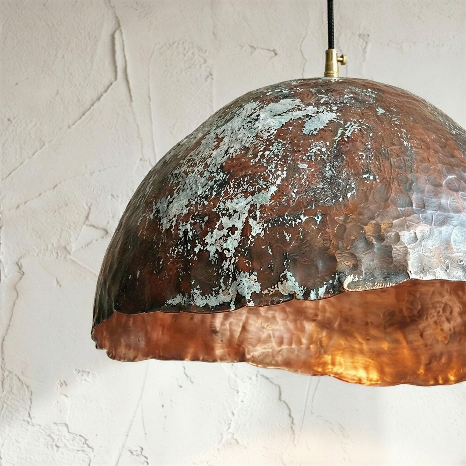Copper pendant light with patina finish on a white wall