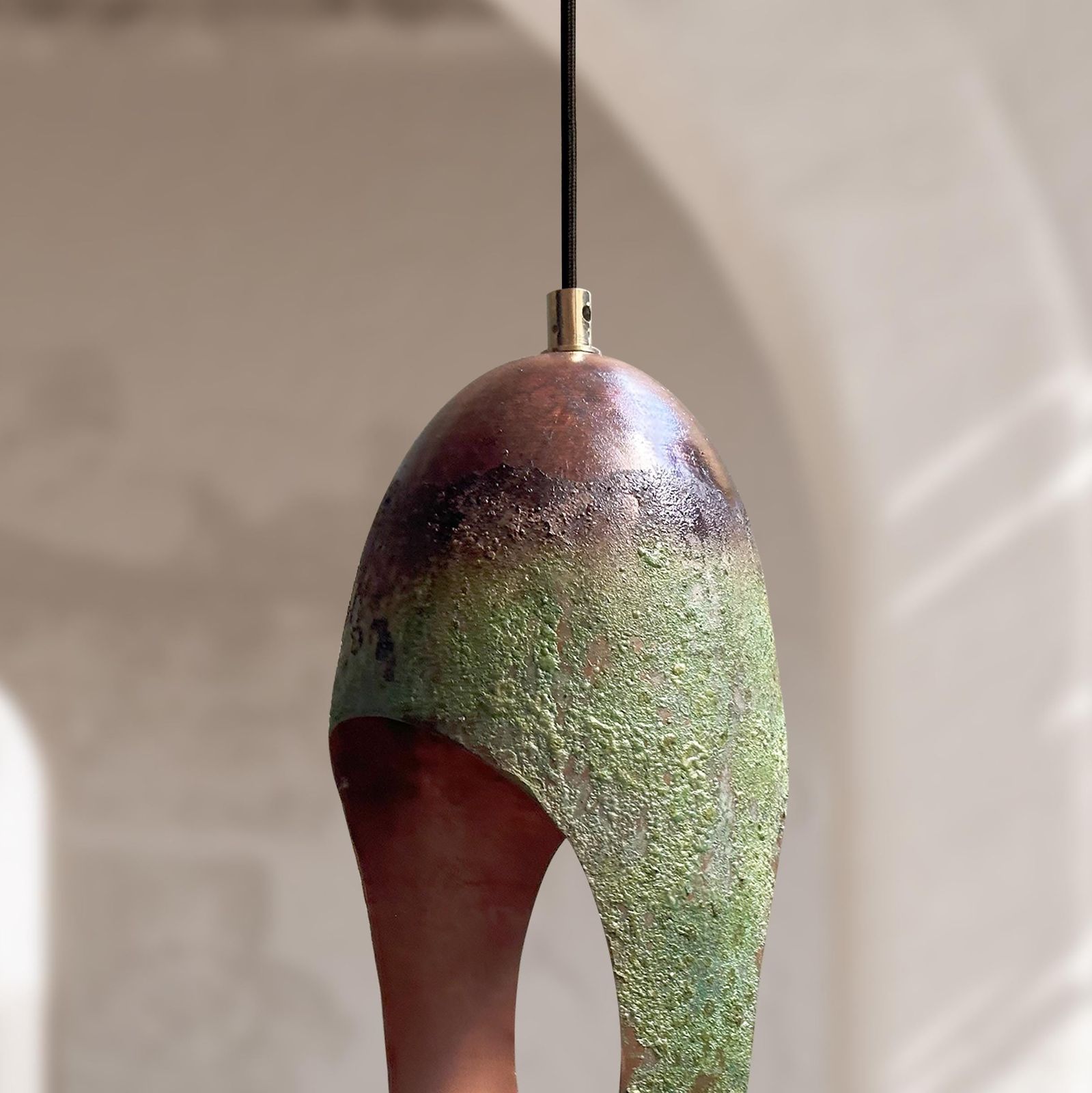 Ceramic pendant light with green and brown gradient on a neutral background