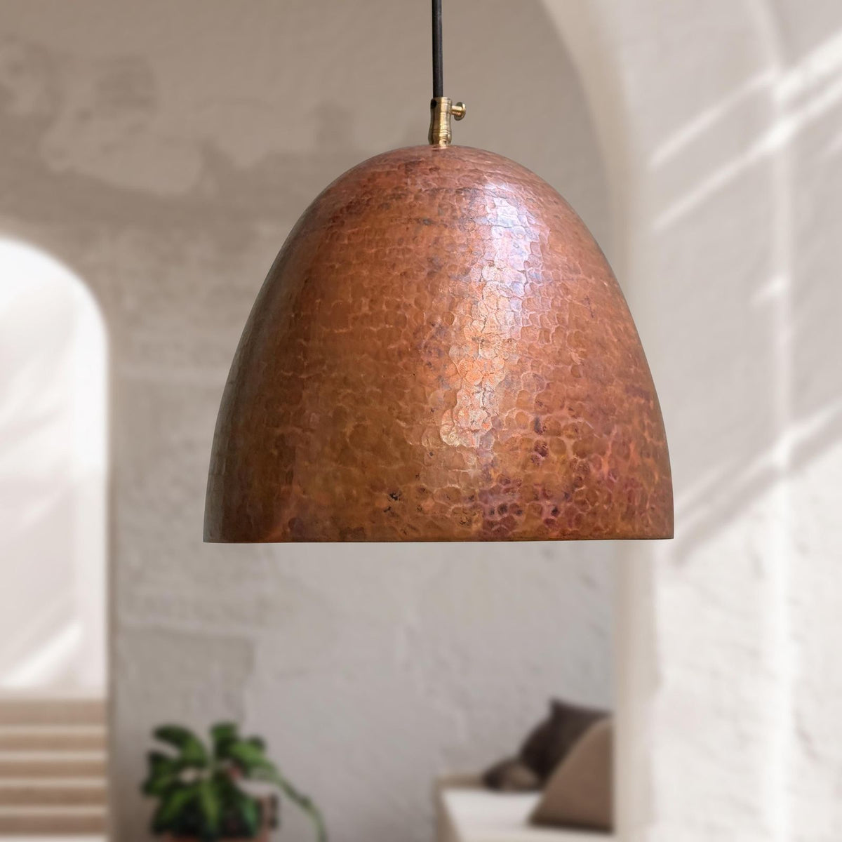 Copper pendant light hanging in a room with a neutral background