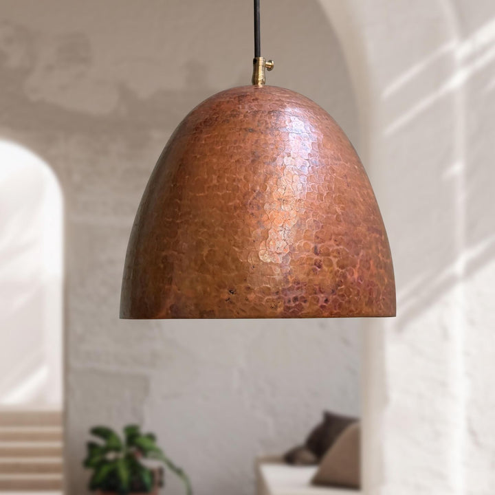 Copper pendant light hanging in a room with a neutral background