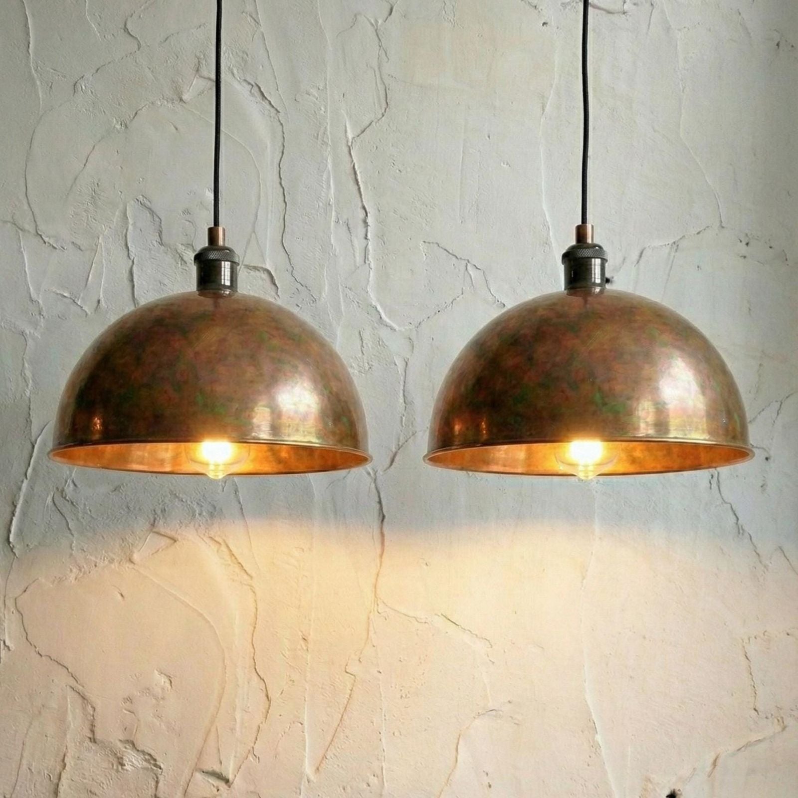 Two copper pendant lights hanging against a textured wall.