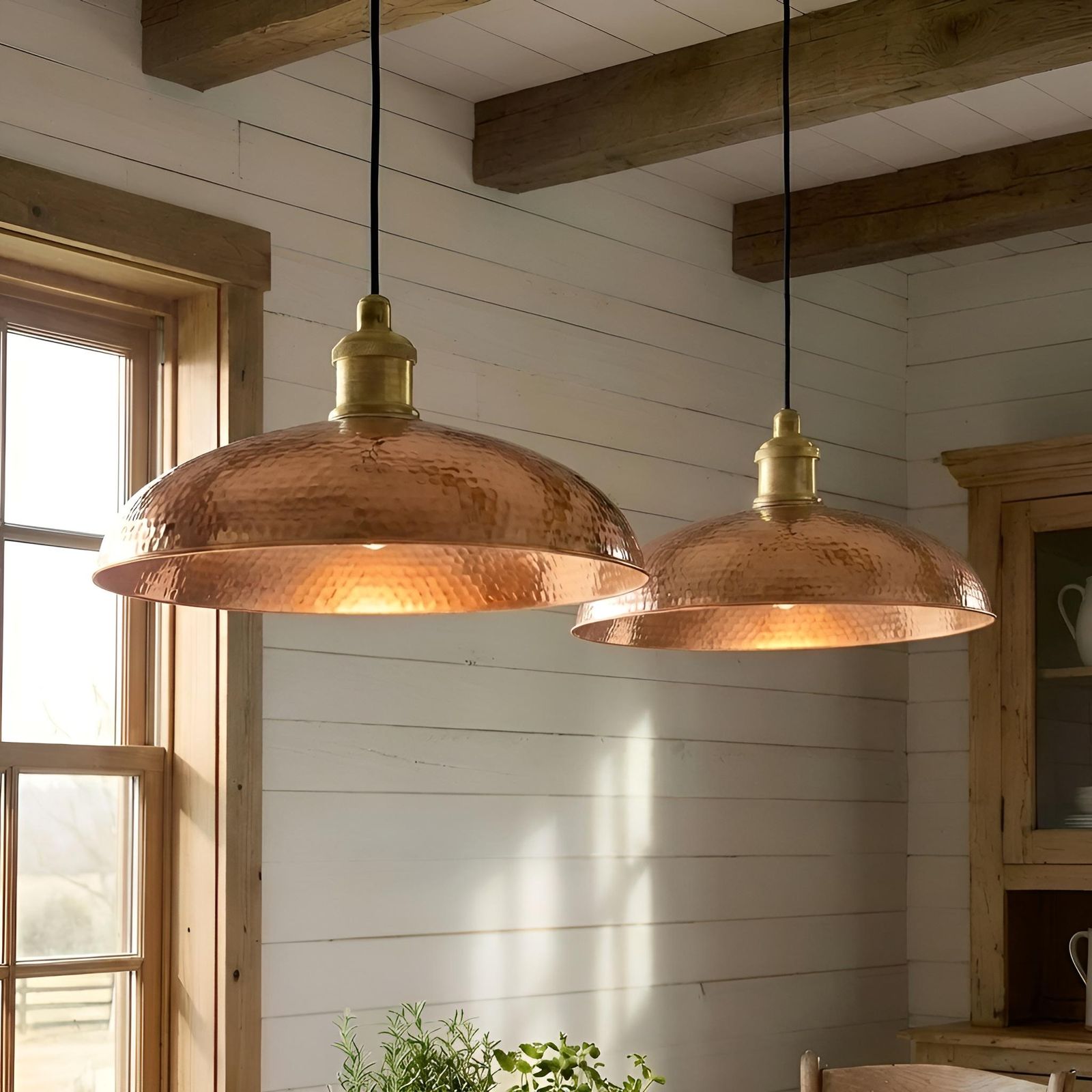 Two copper pendant lights hanging in a room with wooden beams and a window.