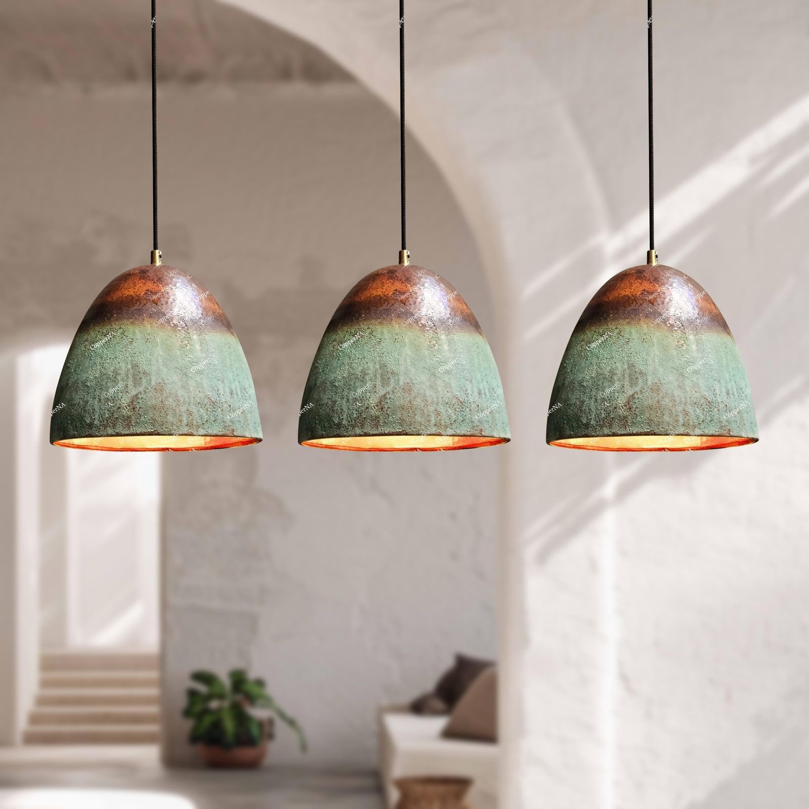 Three pendant lights with green and brown distressed finish hanging in a room with white walls and a plant.