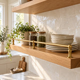Solid brass kitchen shelf rail with ceramics and spice jars on an oak shelf