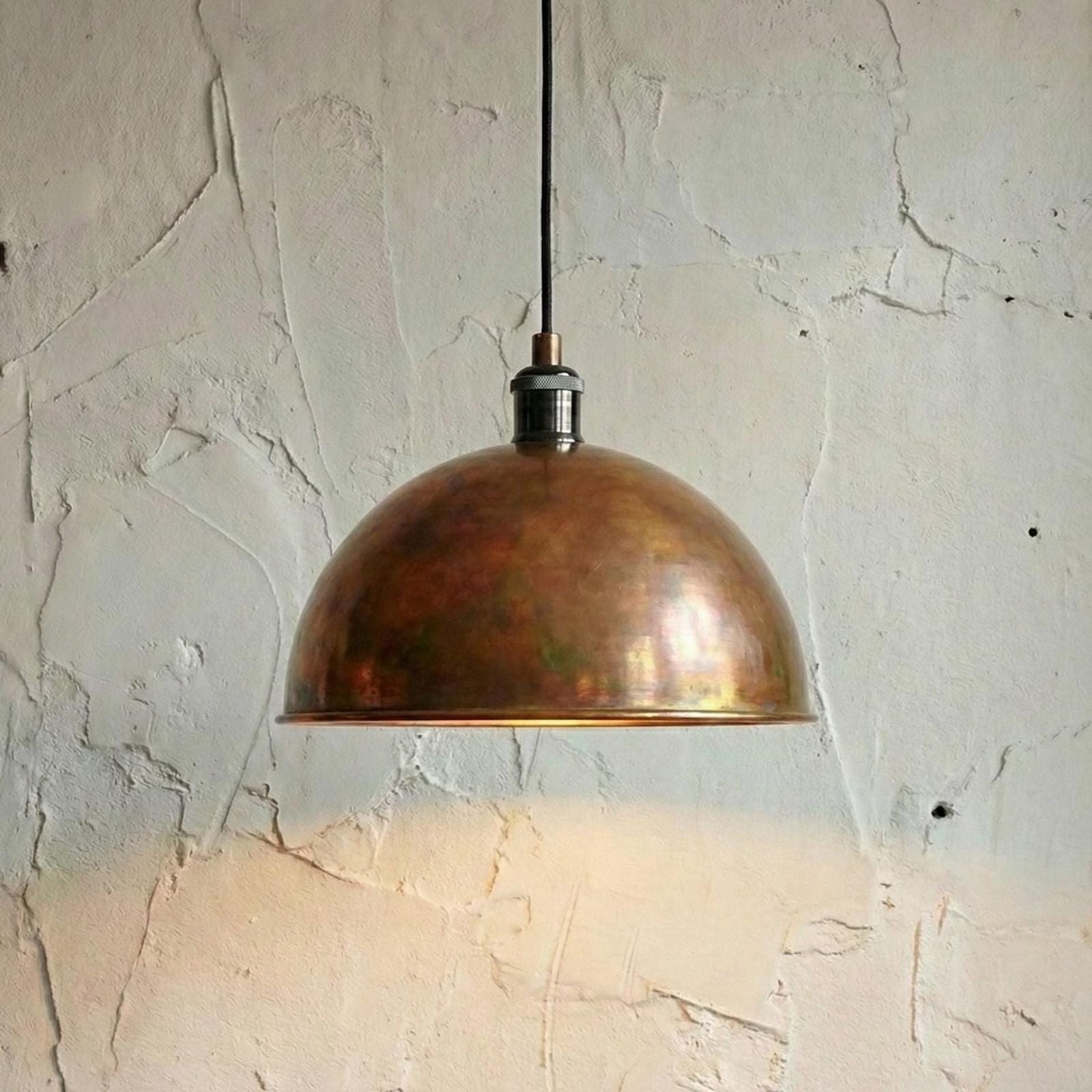 Bronze pendant light hanging against a textured wall.