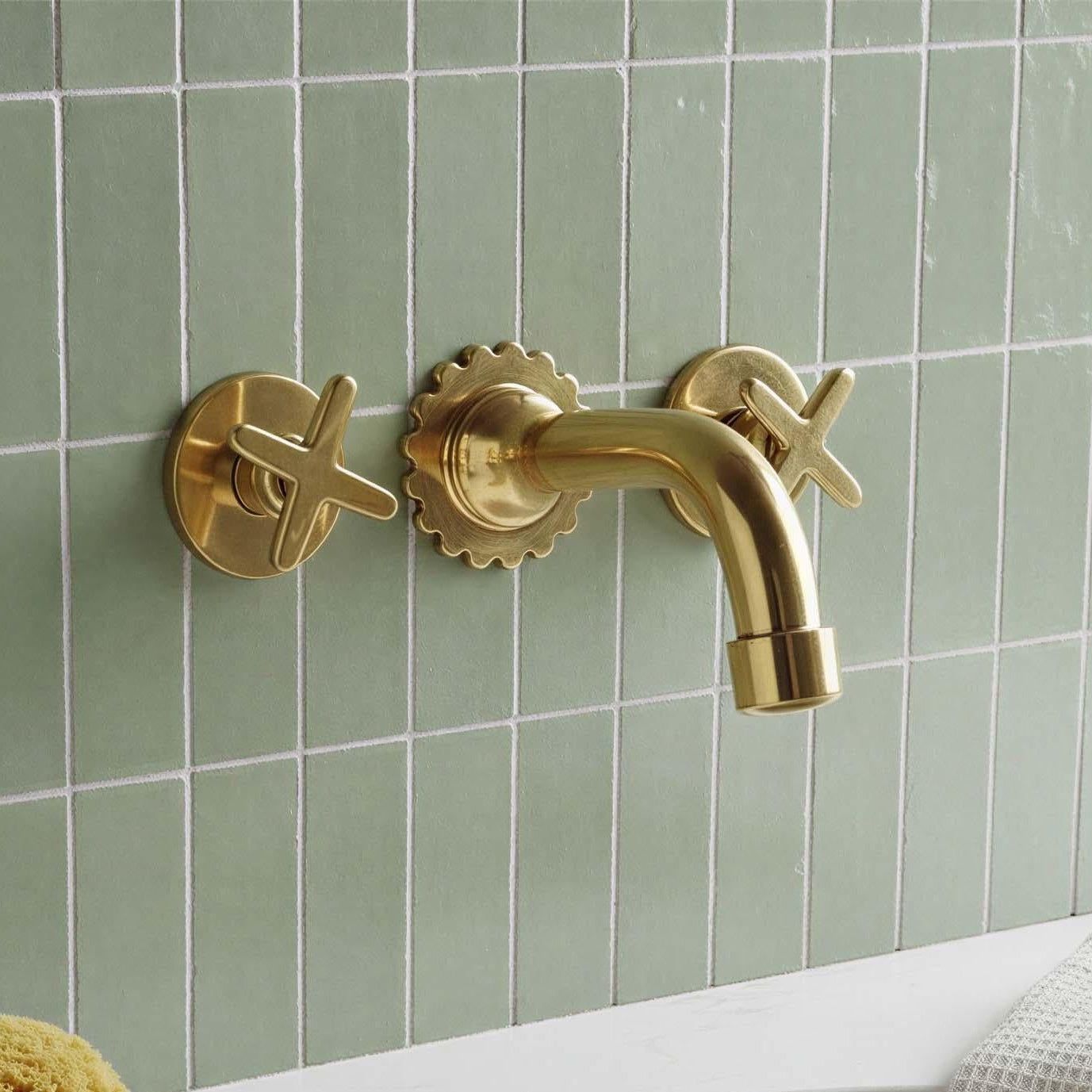 Gold faucet and handles on a green tiled wall