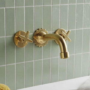 Gold faucet and handles on a green tiled wall