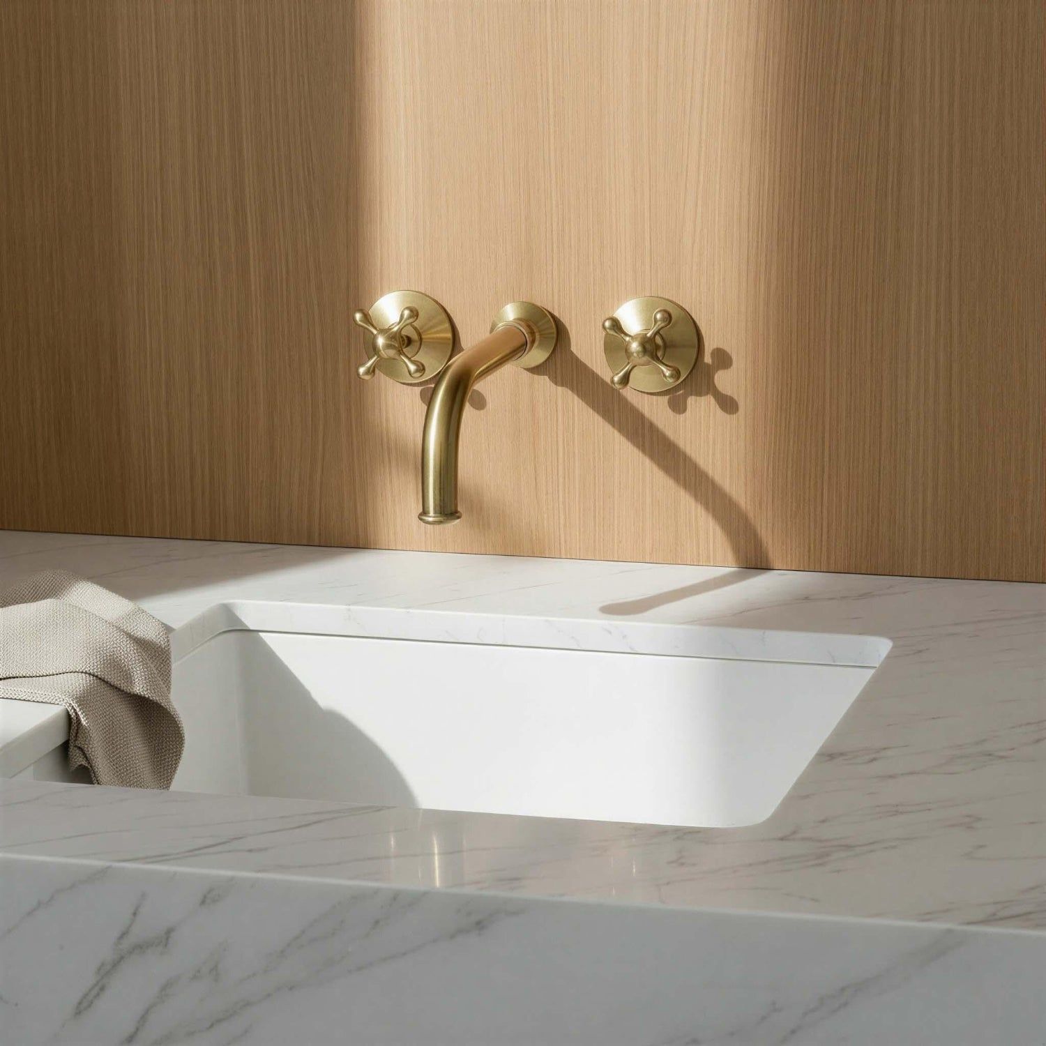 Gold faucet on a white sink with a wooden wall background