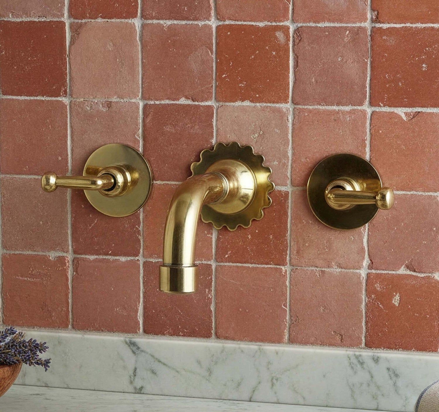 Gold bathroom faucet and handles on a tiled wall