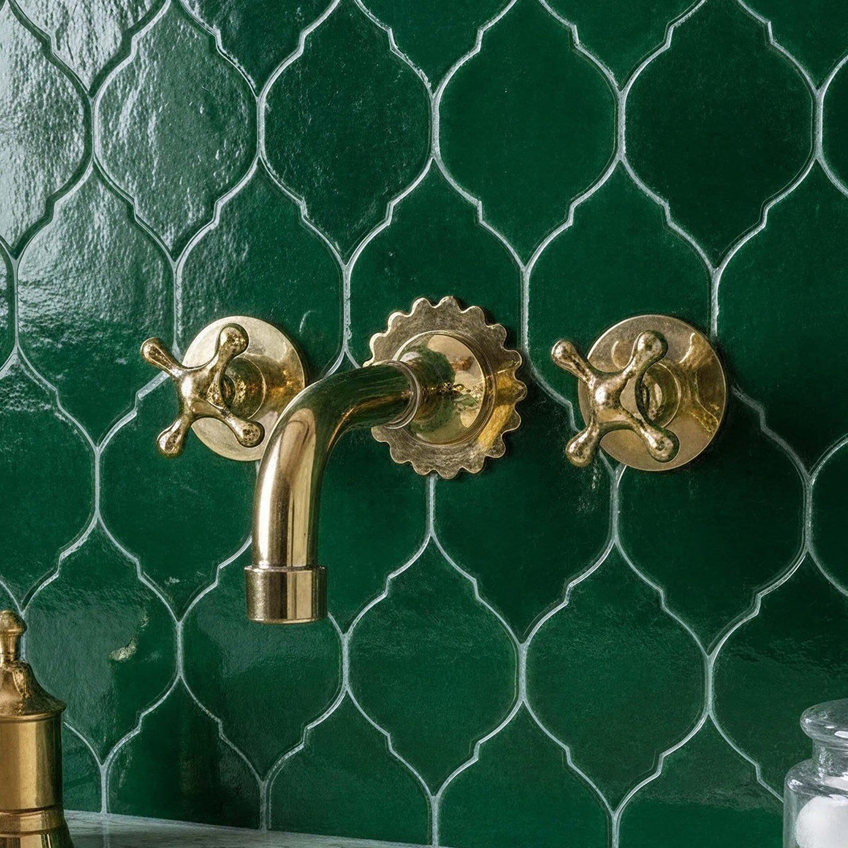 Gold faucet and handles on a green tiled wall