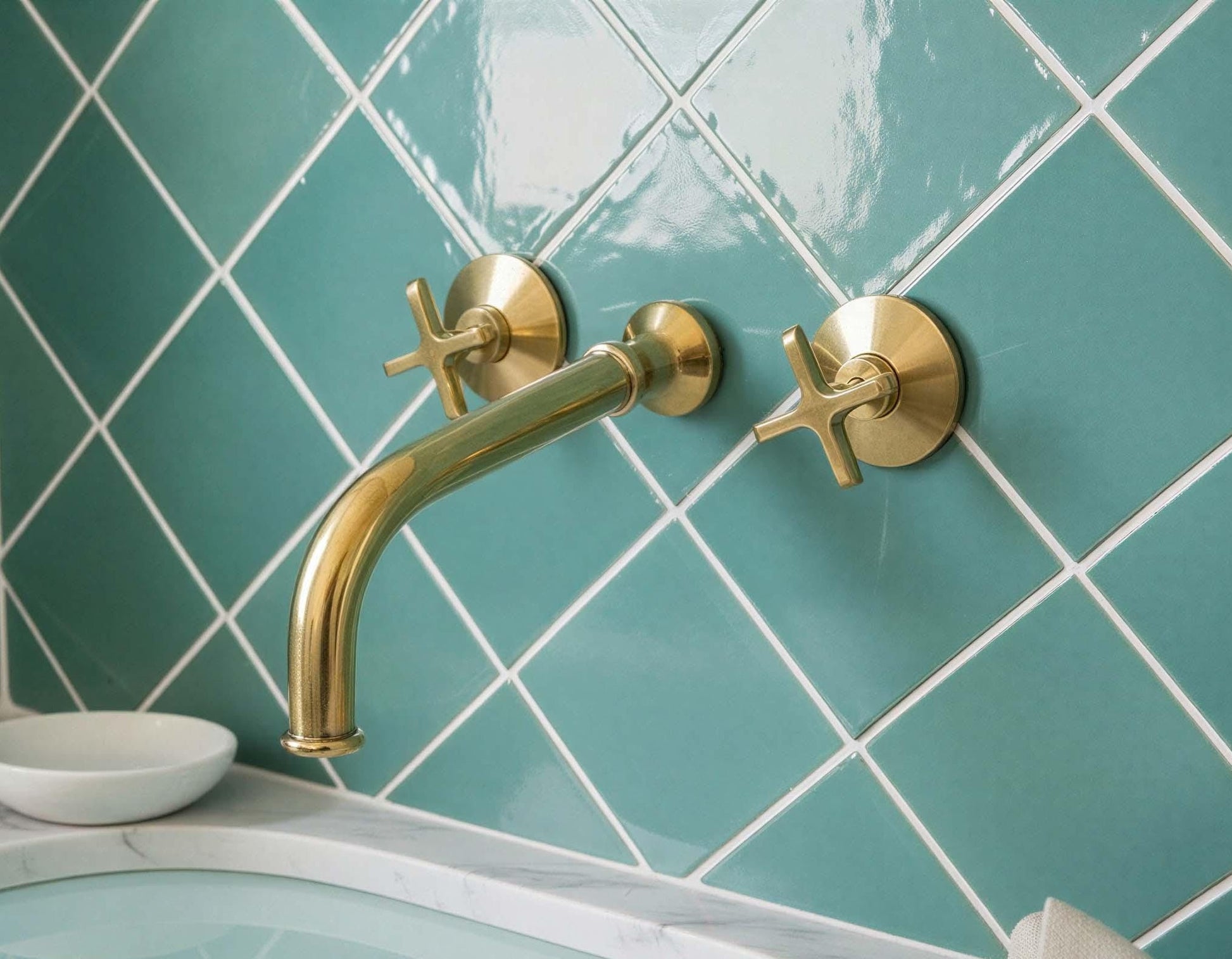 Gold faucet and handles on a teal tiled wall