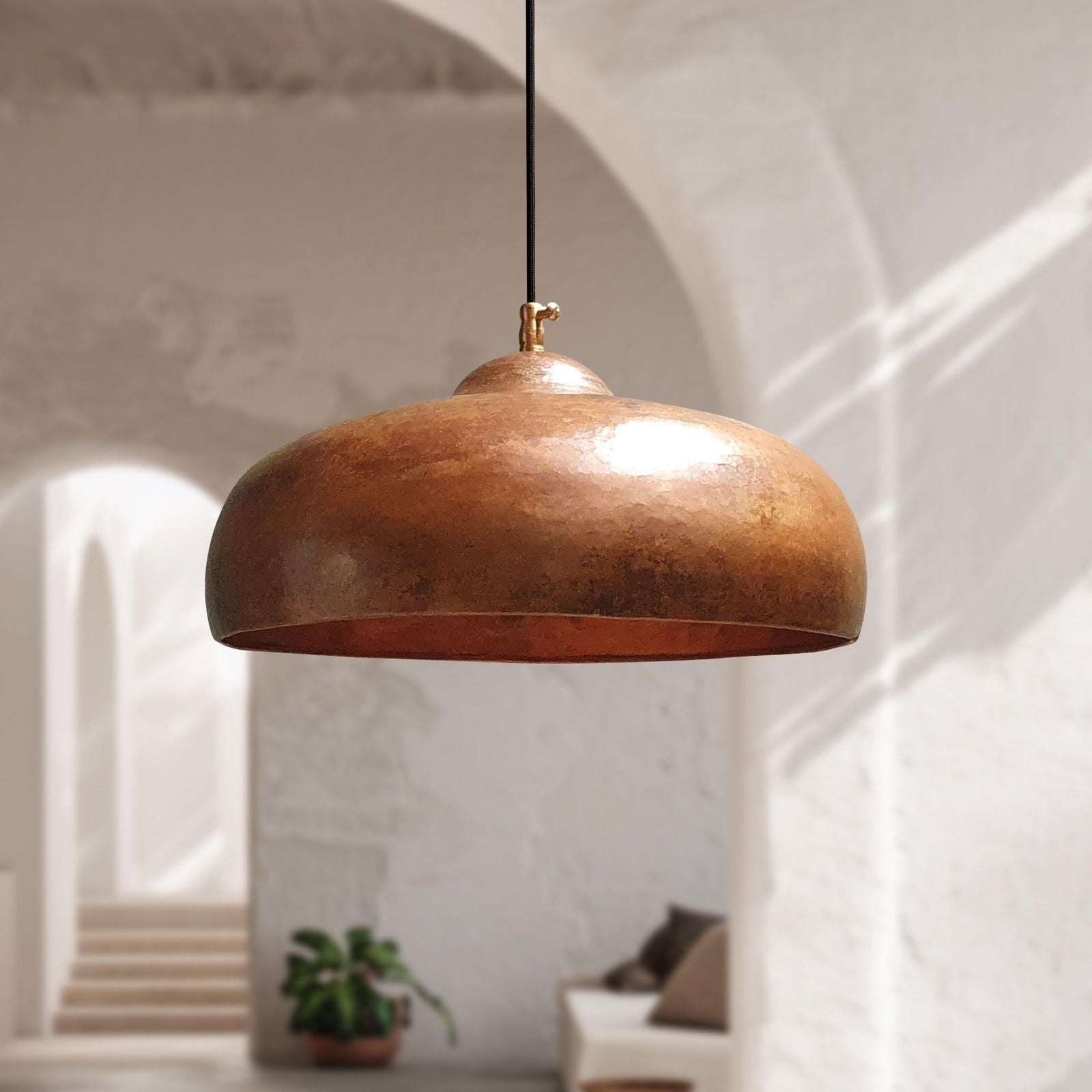 Bronze pendant light hanging in a room with a blurred background