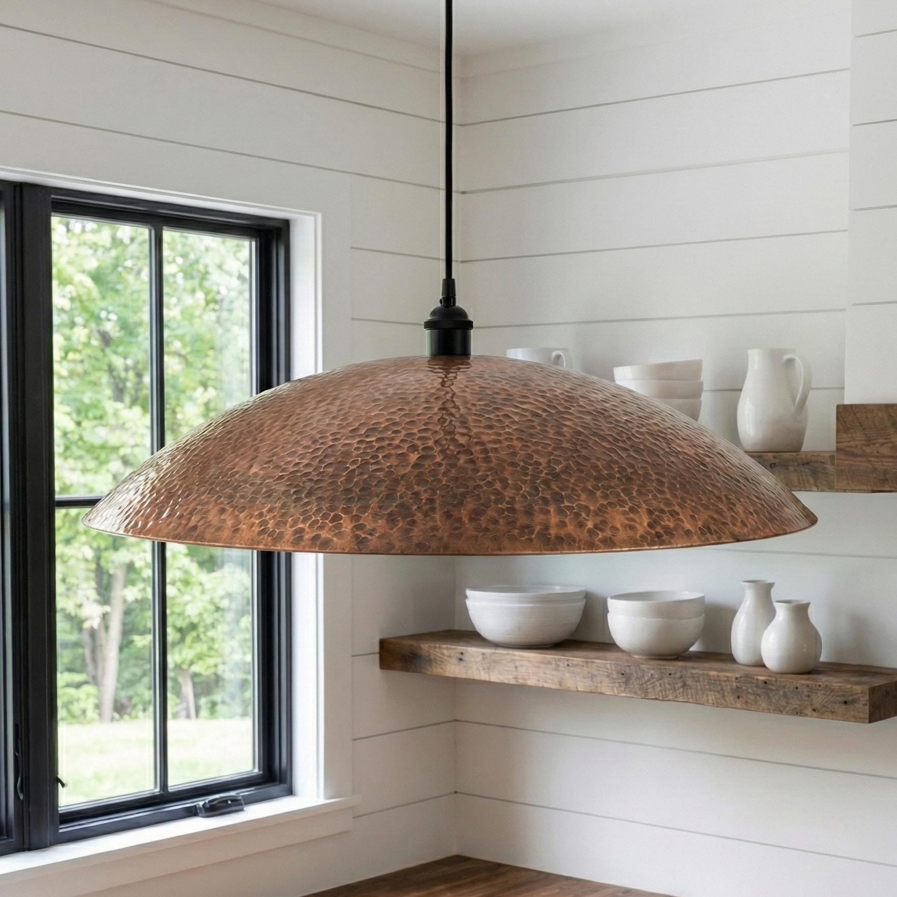 Copper pendant light hanging in a room with a window and shelves.
