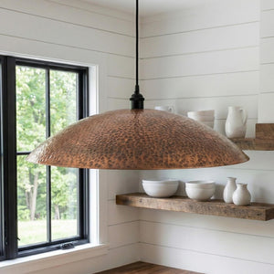 Copper pendant light hanging in a room with a window and shelves.