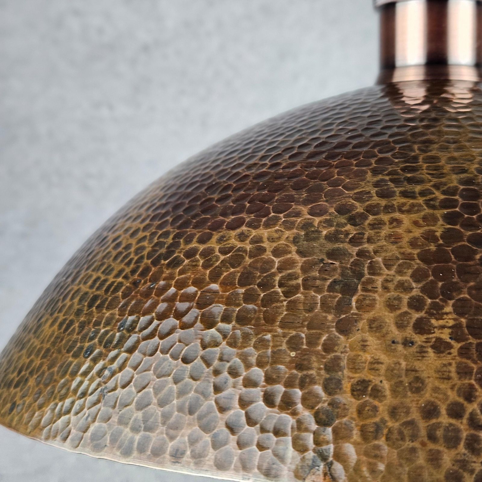 Close-up of a textured bronze lampshade against a gray background