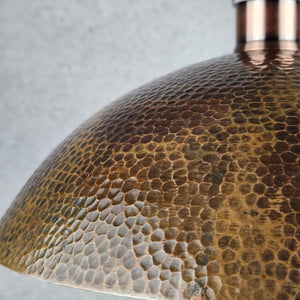 Close-up of a textured bronze lampshade against a gray background