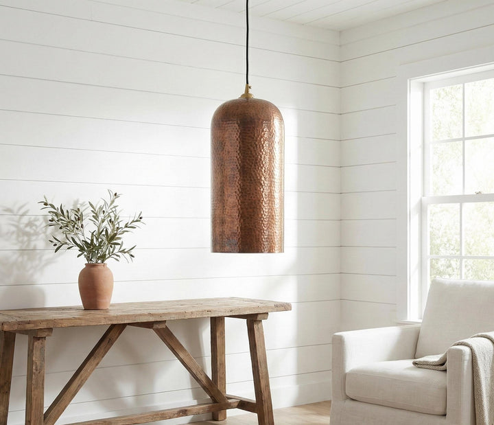 Living room with wooden table, potted plant, and hanging copper pendant light.
