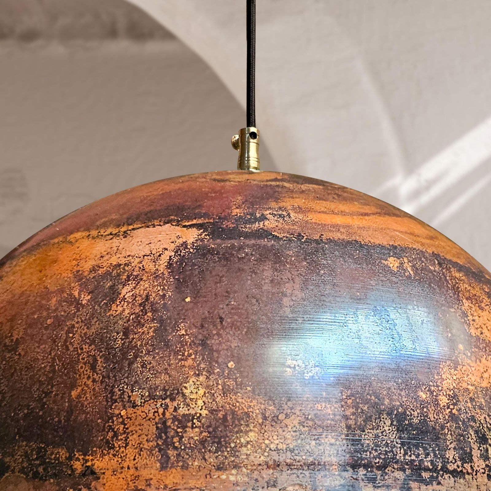 Rust-colored pendant light with a textured surface against a neutral background