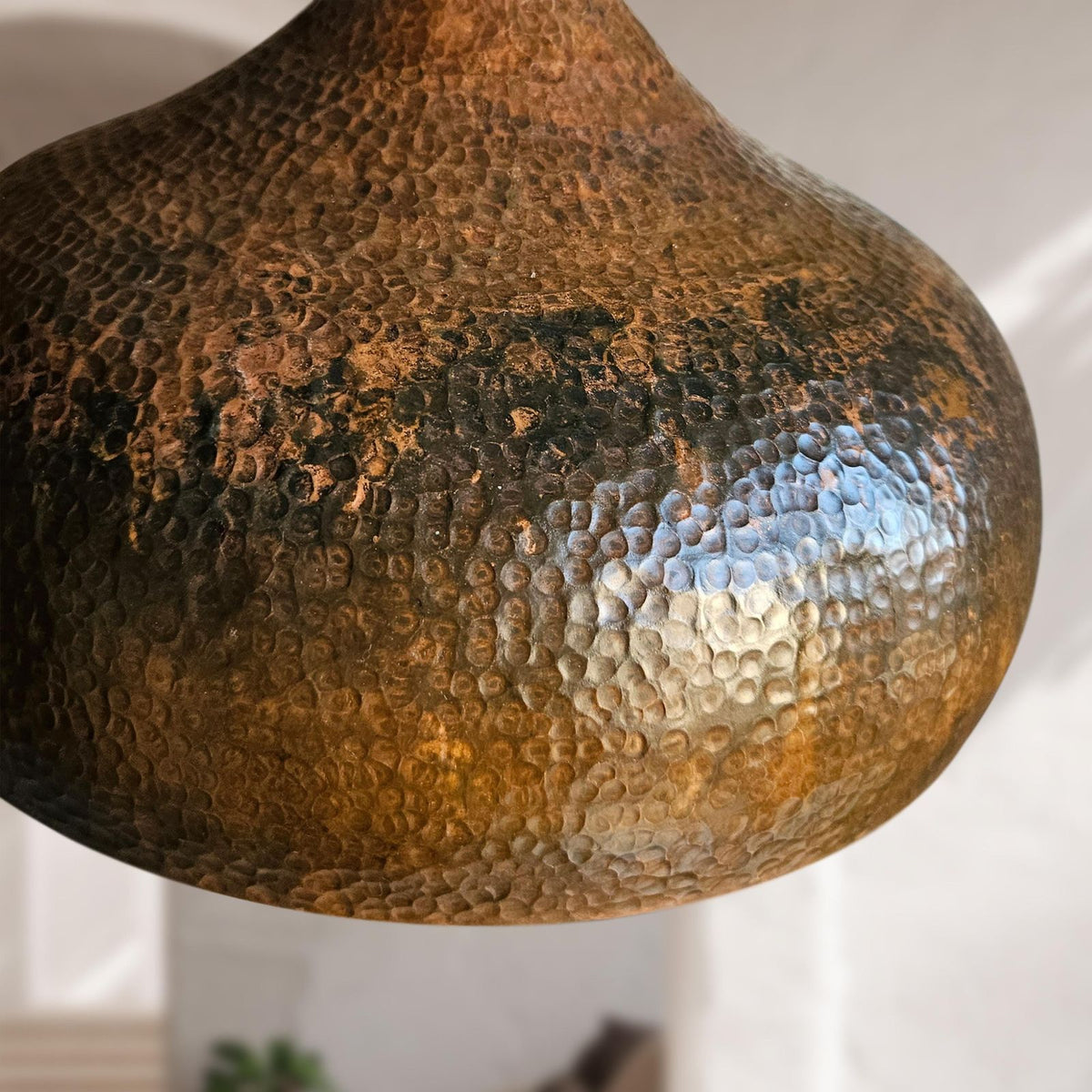 Close-up of a textured copper pendant light against a neutral background