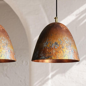 Two rustic copper pendant lights hanging against a white wall.