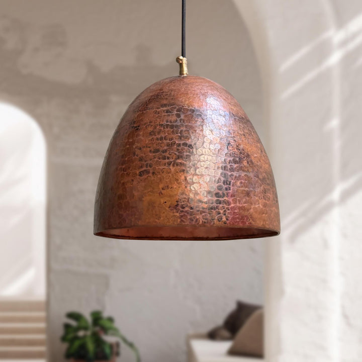 Copper pendant light hanging in a room with a neutral background
