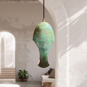 Green ceramic pendant light hanging in a room with a neutral decor.