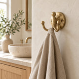 Vintage solid brass double robe hook with linen towel in a neutral bathroom